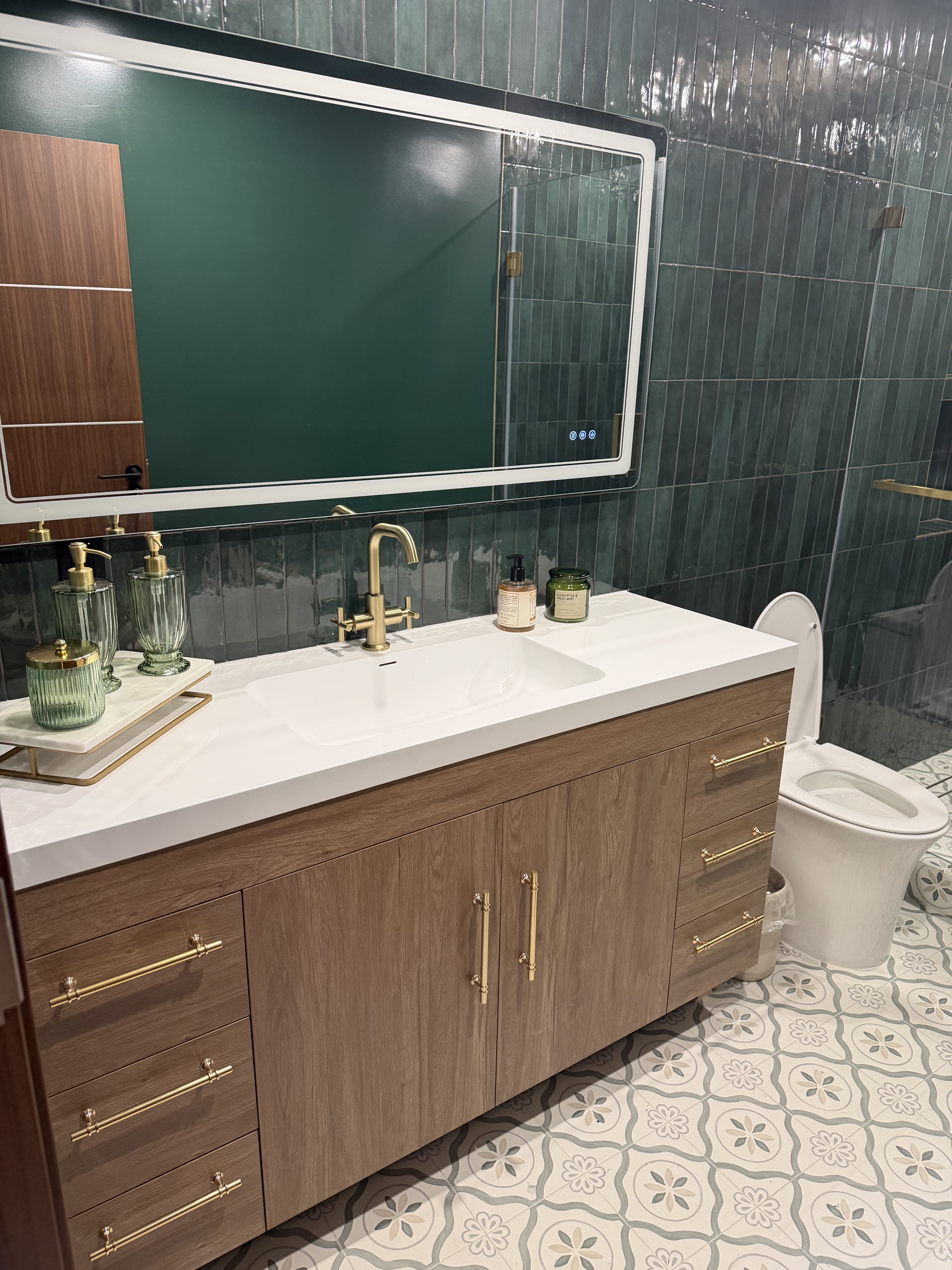 Bathroom remodel with green tile, brass fixtures, and a floating vanity